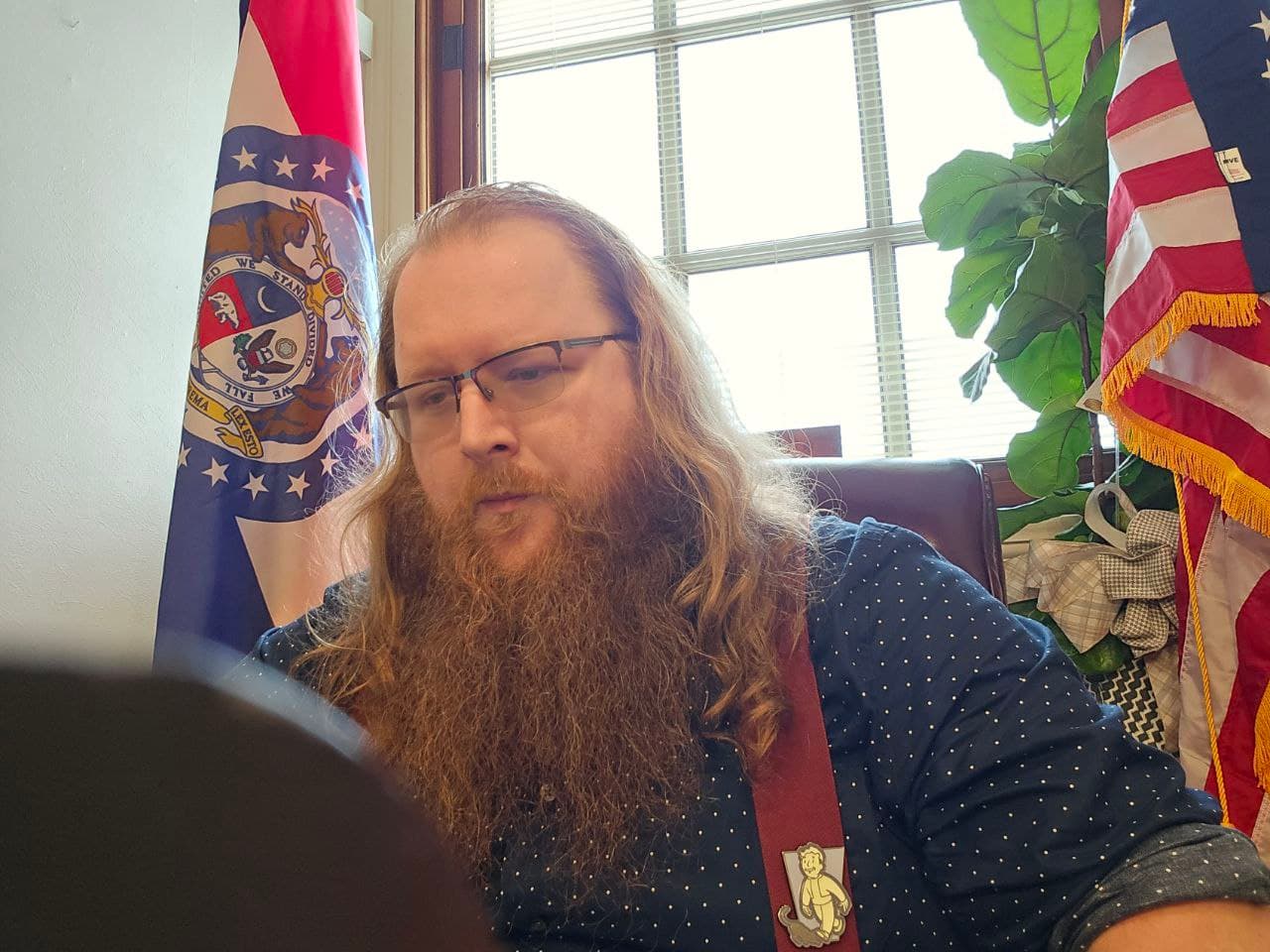 Clayton Harbison at desk with Missouri and U.S. flags